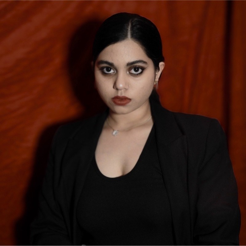 A young woman with dark hair looking directly at the camera with a confident expression.