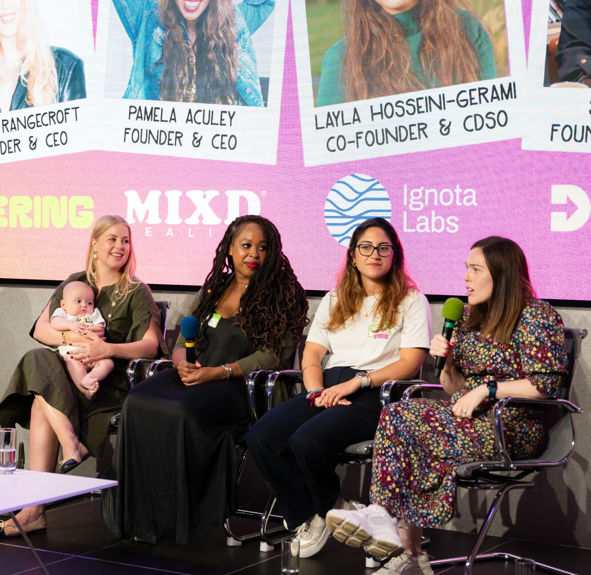 A panel of 4 women at Next Tech Fest. The screen behind them shows the names PAMELA ACULEY FOUNDER & CEO and LAYLA HOSSEINI-GERAMI CO-FOUNDER & CDSO, along with logos for MIXD REALTY and Ignota Labs.