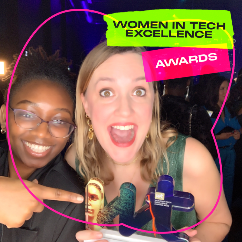 Emily Hall-Strutt of Next Tech Girls holding her award at the Women in Tech Awards with an elated expression. A woman is smiling next to her and pointing at her award.